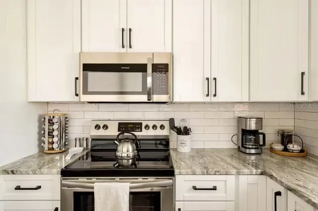 a kitchen with granite countertop white cabinets and white appliances