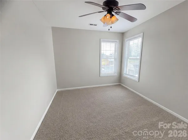 an empty room with windows and chandelier fan