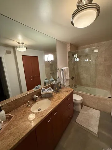 a bathroom with a granite countertop sink toilet a mirror a bathtub and shower