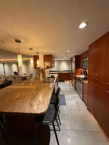 a large kitchen with kitchen island a stove a sink a refrigerator and chairs