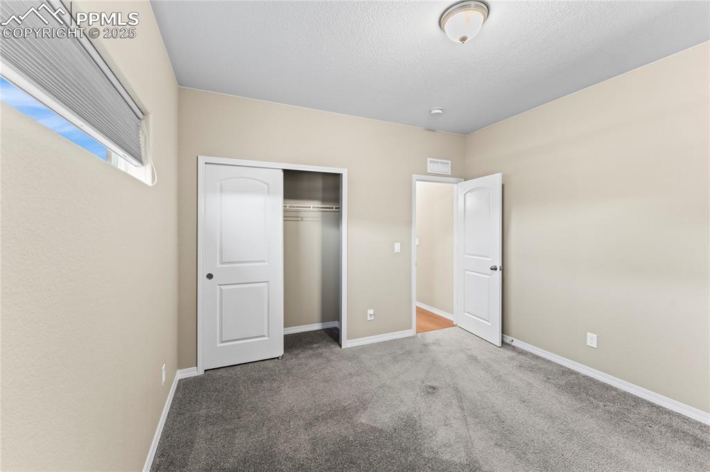 6208 Ashmore Road Colorado Springs, CO 80927 - Photo 11 of 50 Unfurnished bedroom with carpet floors, a closet, and a textured ceiling