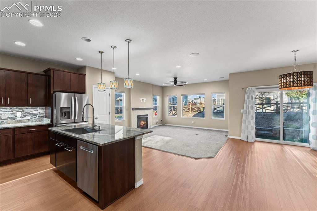 6208 Ashmore Road Colorado Springs, CO 80927 - Photo 17 of 50 Kitchen with pendant lighting, open floor plan, dark stone countertops, an island with sink, and dark brown cabinetry