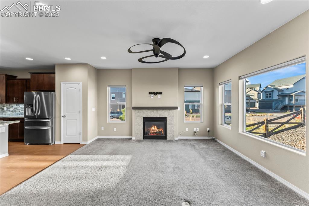 6208 Ashmore Road Colorado Springs, CO 80927 - Photo 21 of 50 Unfurnished living room featuring recessed lighting, a ceiling fan, a tile fireplace, and light colored carpet