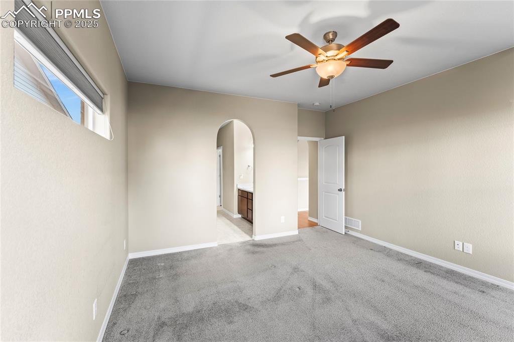 6208 Ashmore Road Colorado Springs, CO 80927 - Photo 24 of 50 Spare room with light colored carpet, arched walkways, and ceiling fan
