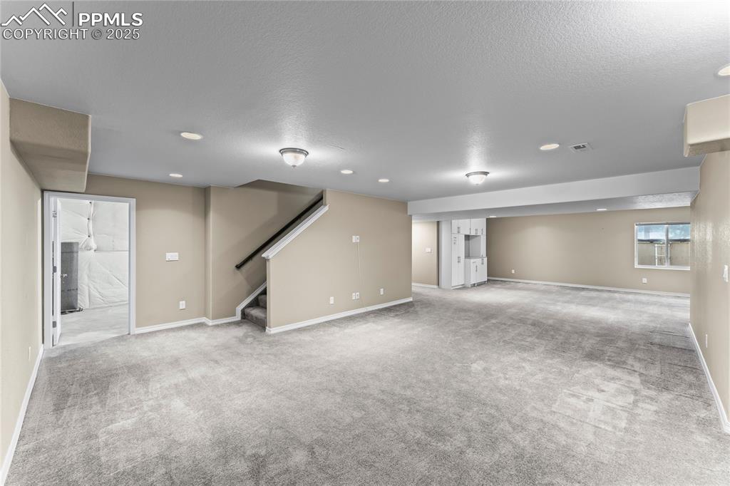 6208 Ashmore Road Colorado Springs, CO 80927 - Photo 31 of 50 Basement with light colored carpet, stairs, and a textured ceiling