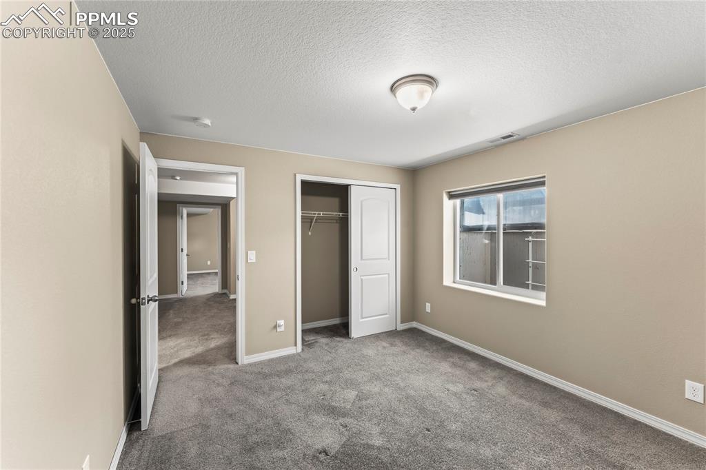 6208 Ashmore Road Colorado Springs, CO 80927 - Photo 38 of 50 Unfurnished bedroom featuring carpet flooring, a closet, and a textured ceiling