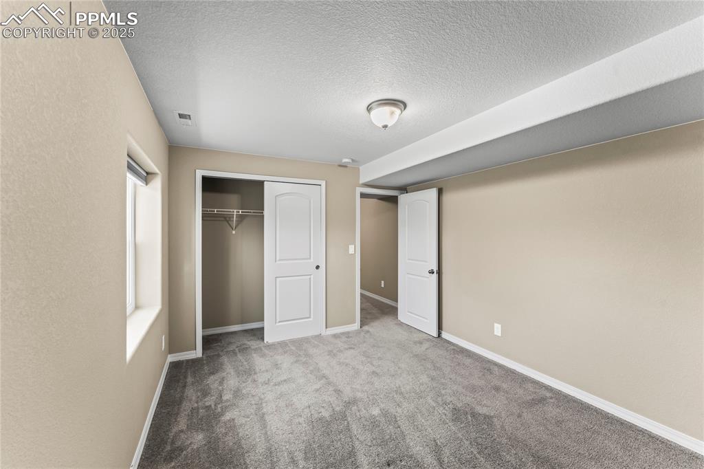 6208 Ashmore Road Colorado Springs, CO 80927 - Photo 40 of 50 Unfurnished bedroom featuring carpet floors, a closet, and a textured ceiling