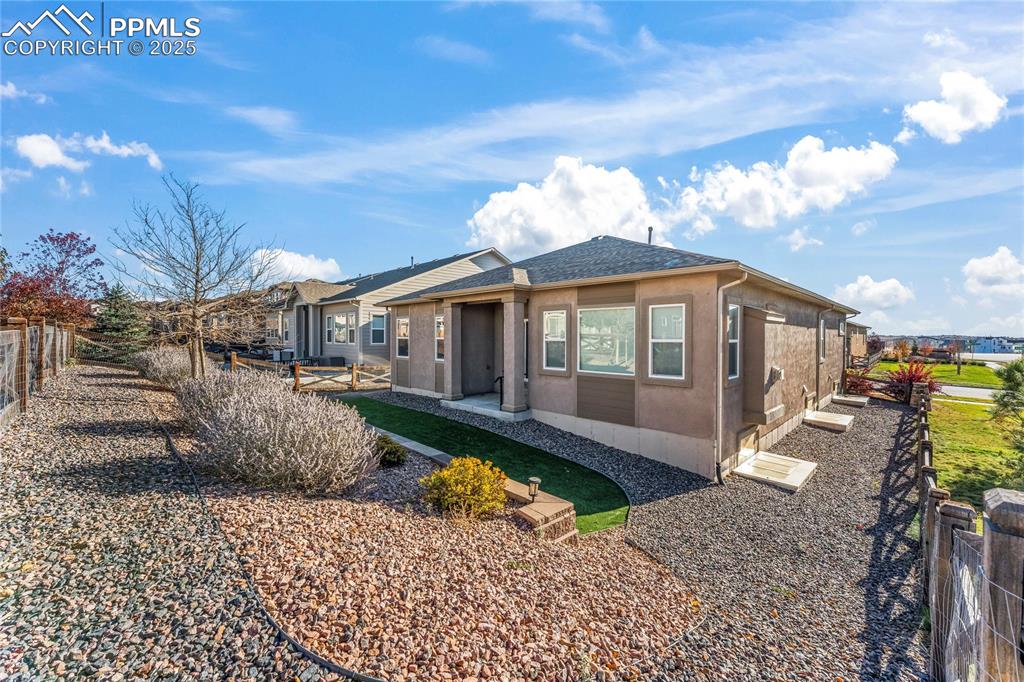 6208 Ashmore Road Colorado Springs, CO 80927 - Photo 43 of 50 View of front facade featuring a fenced backyard, roof with shingles, stucco siding, and a patio area