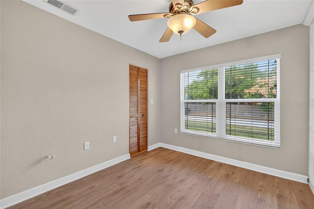 302 Leafwood Road Tarpon Springs, FL 34689 - Photo 25 of 55 an empty room with wooden floor chandelier fan and windows