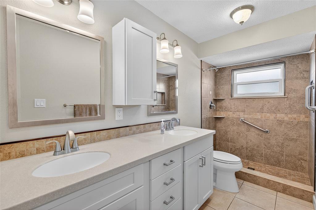 302 Leafwood Road Tarpon Springs, FL 34689 - Photo 28 of 55 a bathroom with a granite countertop double vanity sink a mirror and a toilet