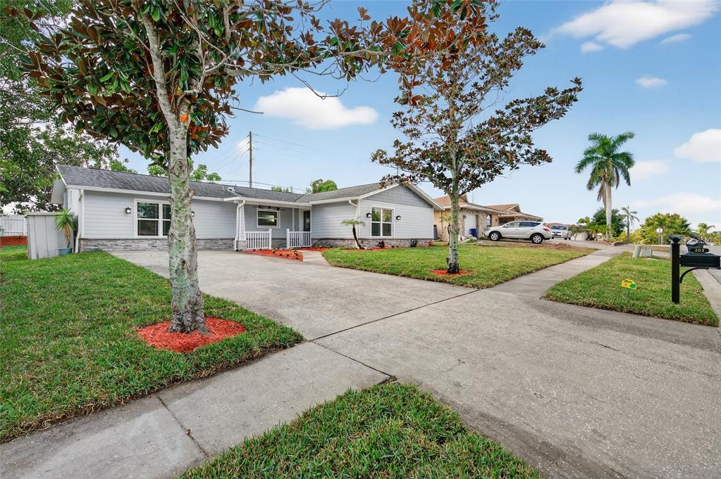 302 Leafwood Road Tarpon Springs, FL 34689 - Photo 4 of 55 a house with sign board and garden