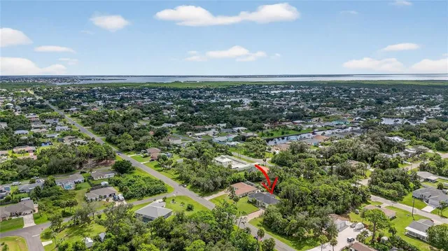 an aerial view of a houses with a yard and lake view in back