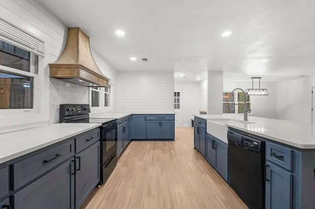 an empty room with wooden floor cabinet and windows