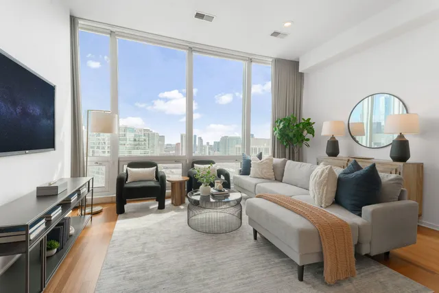 a living room with furniture a flat screen tv and a floor to ceiling window