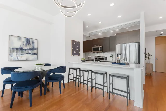 a kitchen with stainless steel appliances kitchen island granite countertop a table chairs and a refrigerator