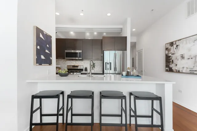 a kitchen with stainless steel appliances a dining table chairs and a refrigerator