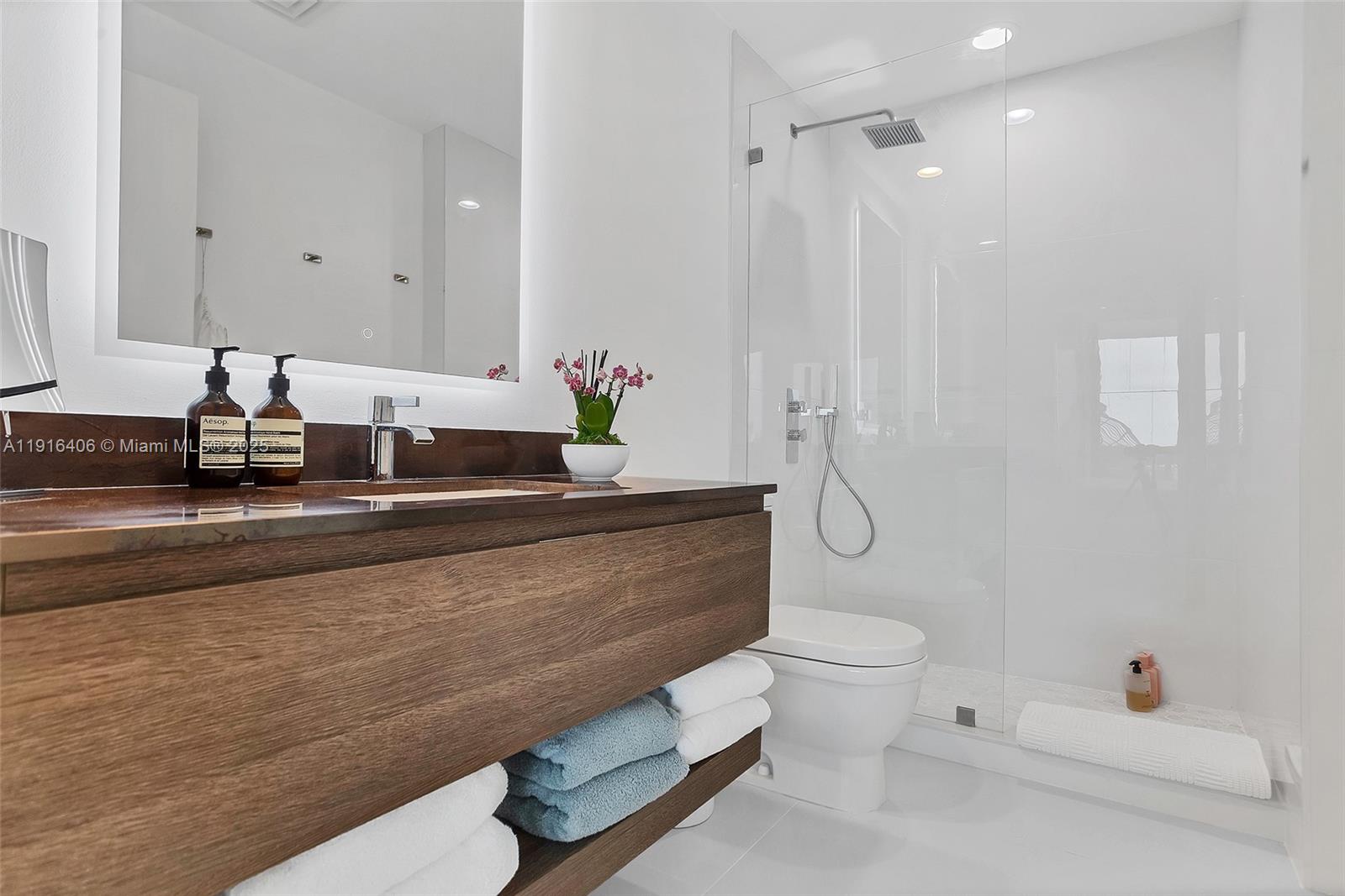 350 Ocean Drive, Unit 405N Key Biscayne, FL 33149 - Photo 21 of 34 a bathroom with a granite countertop sink a toilet and a mirror