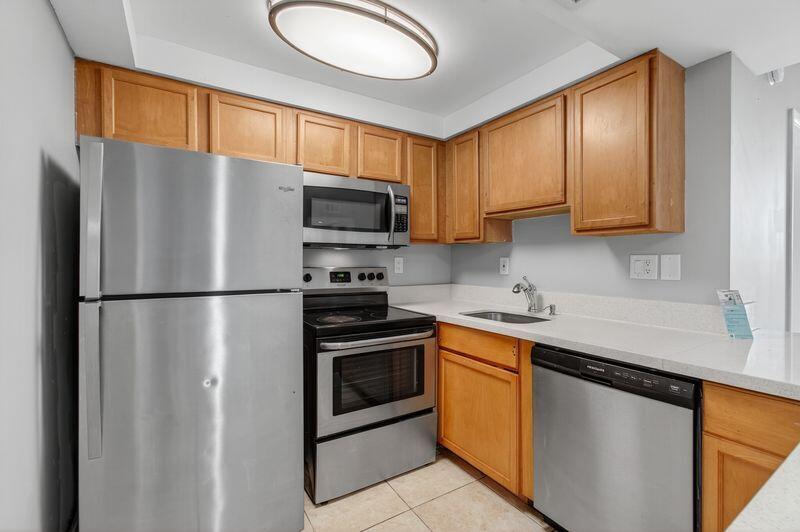 744 Executive Center Drive, Unit 11 West Palm Beach, FL 33401 - Photo 2 of 29 a kitchen with stainless steel appliances granite countertop a refrigerator stove a sink dishwasher and microwave