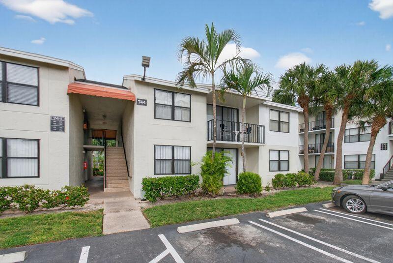 744 Executive Center Drive, Unit 11 West Palm Beach, FL 33401 - Photo 3 of 29 a view of a white house with a large windows and a yard with plants and a tree