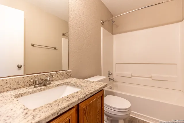 a bathroom with a granite countertop sink toilet and shower