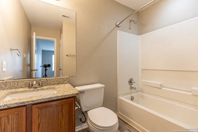 a bathroom with a granite countertop toilet a sink and a bathtub