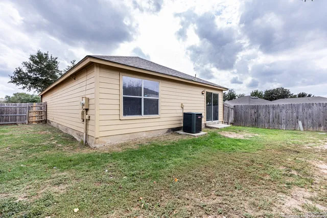 a view of backyard of house with wooden fence