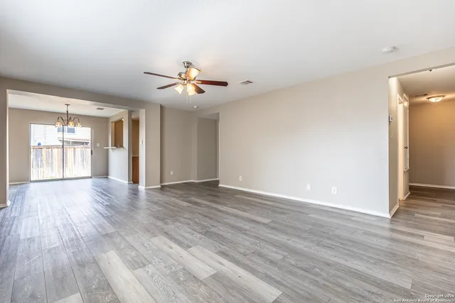 a view of an empty room with window and wooden floor