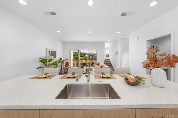 a kitchen with kitchen island granite countertop a sink a counter top space and living room view