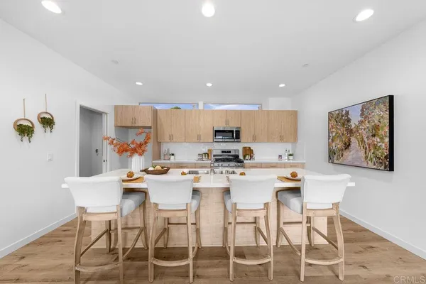 a kitchen with stainless steel appliances kitchen island granite countertop a dining table chairs and white cabinets