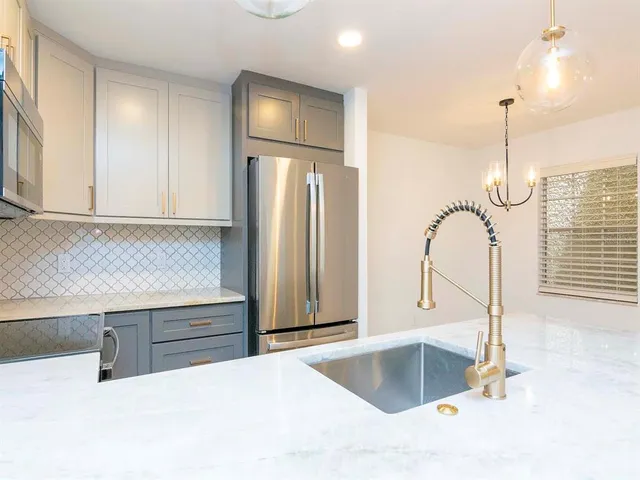 a kitchen with stainless steel appliances granite countertop a refrigerator and a sink