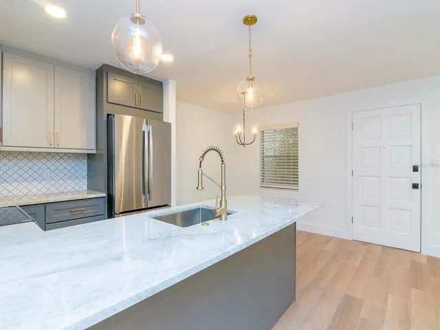 a view of a kitchen with a sink and chandelier stainless steel appliances