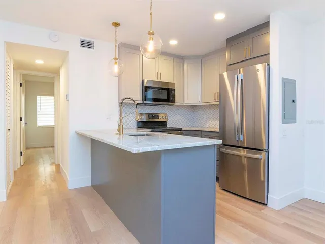 a kitchen with stainless steel appliances granite countertop a refrigerator a stove a sink and a oven