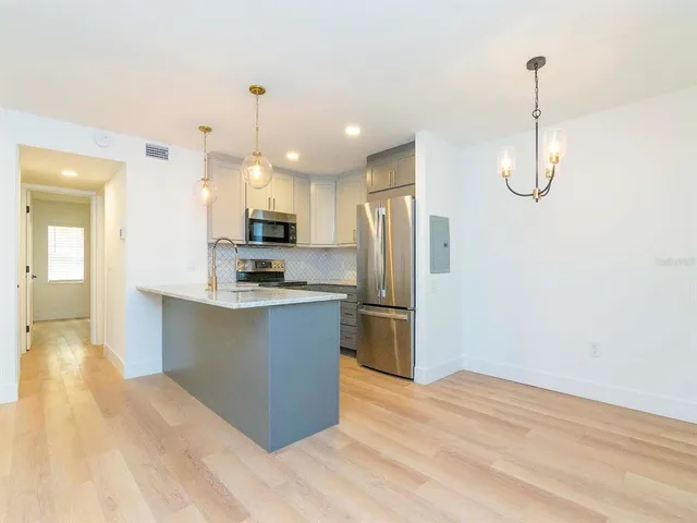 a kitchen with stainless steel appliances kitchen island granite countertop a refrigerator a stove and a sink