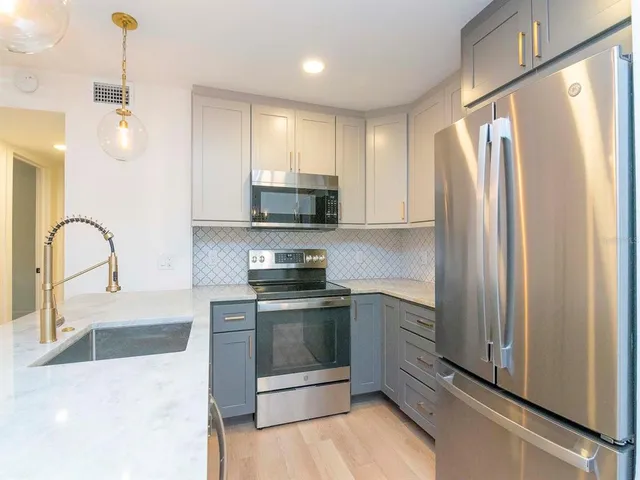 a kitchen with stainless steel appliances granite countertop a stove a sink and a refrigerator