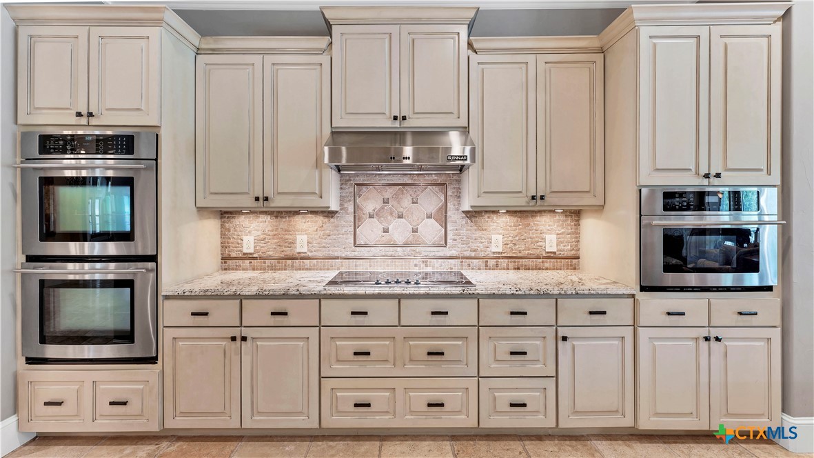 368 Rancho Road New Braunfels, TX 78130 - Photo 12 of 47 a kitchen with granite countertop white cabinets and stainless steel appliances