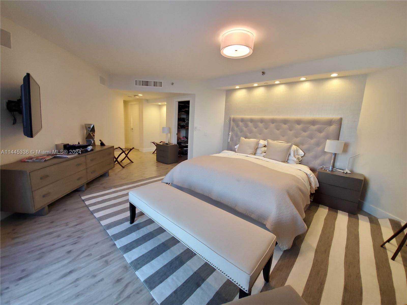 3000 Island Boulevard, Unit 2603 Aventura, FL 33160 - Photo 11 of 28 a spacious bedroom with a bed a mirror and desk