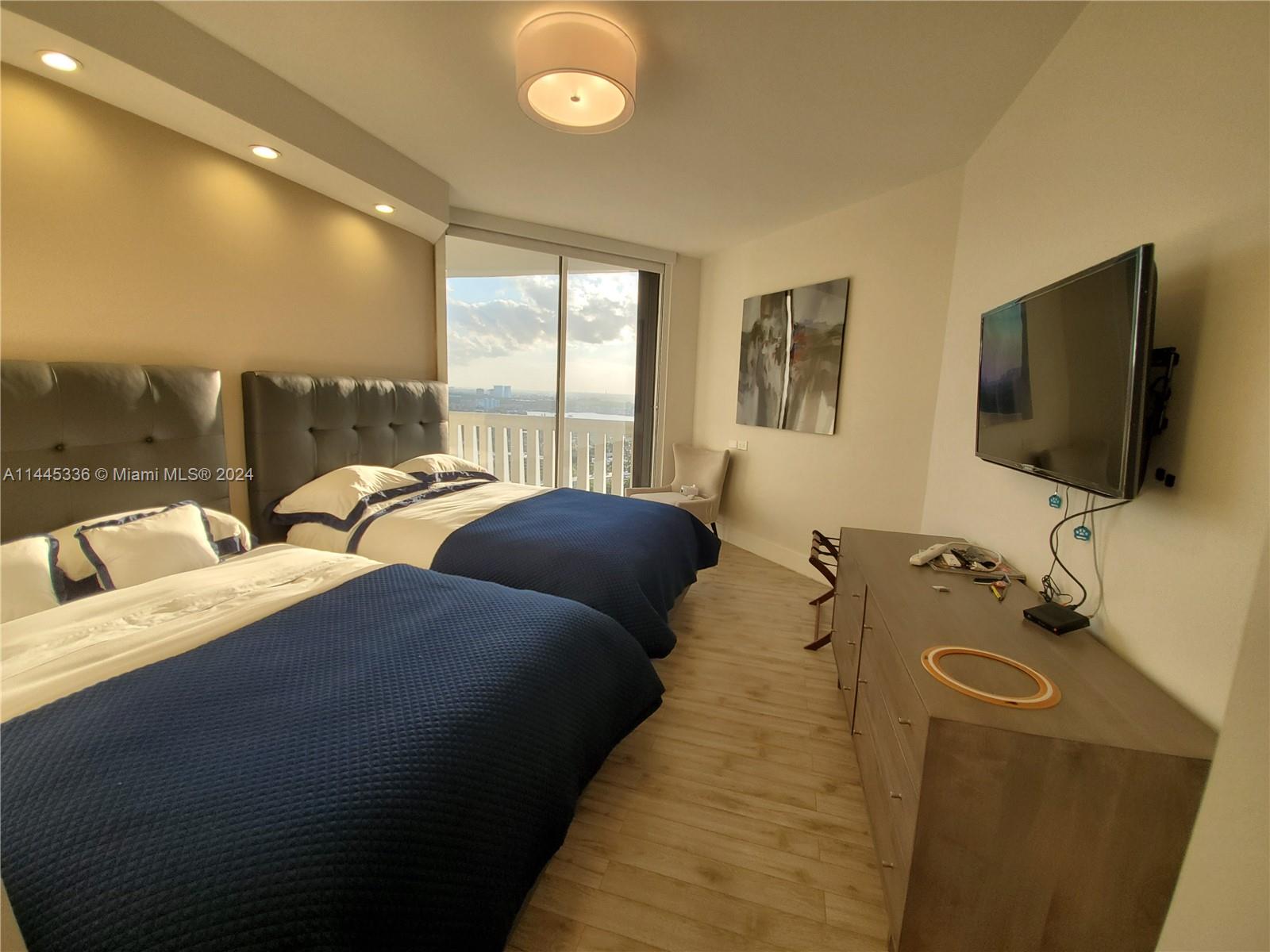 3000 Island Boulevard, Unit 2603 Aventura, FL 33160 - Photo 18 of 28 a bedroom with two beds and a flat screen tv