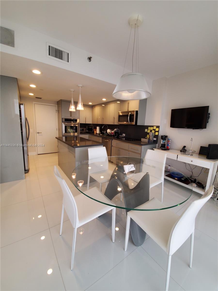 3000 Island Boulevard, Unit 2603 Aventura, FL 33160 - Photo 6 of 28 a kitchen with a table and chairs