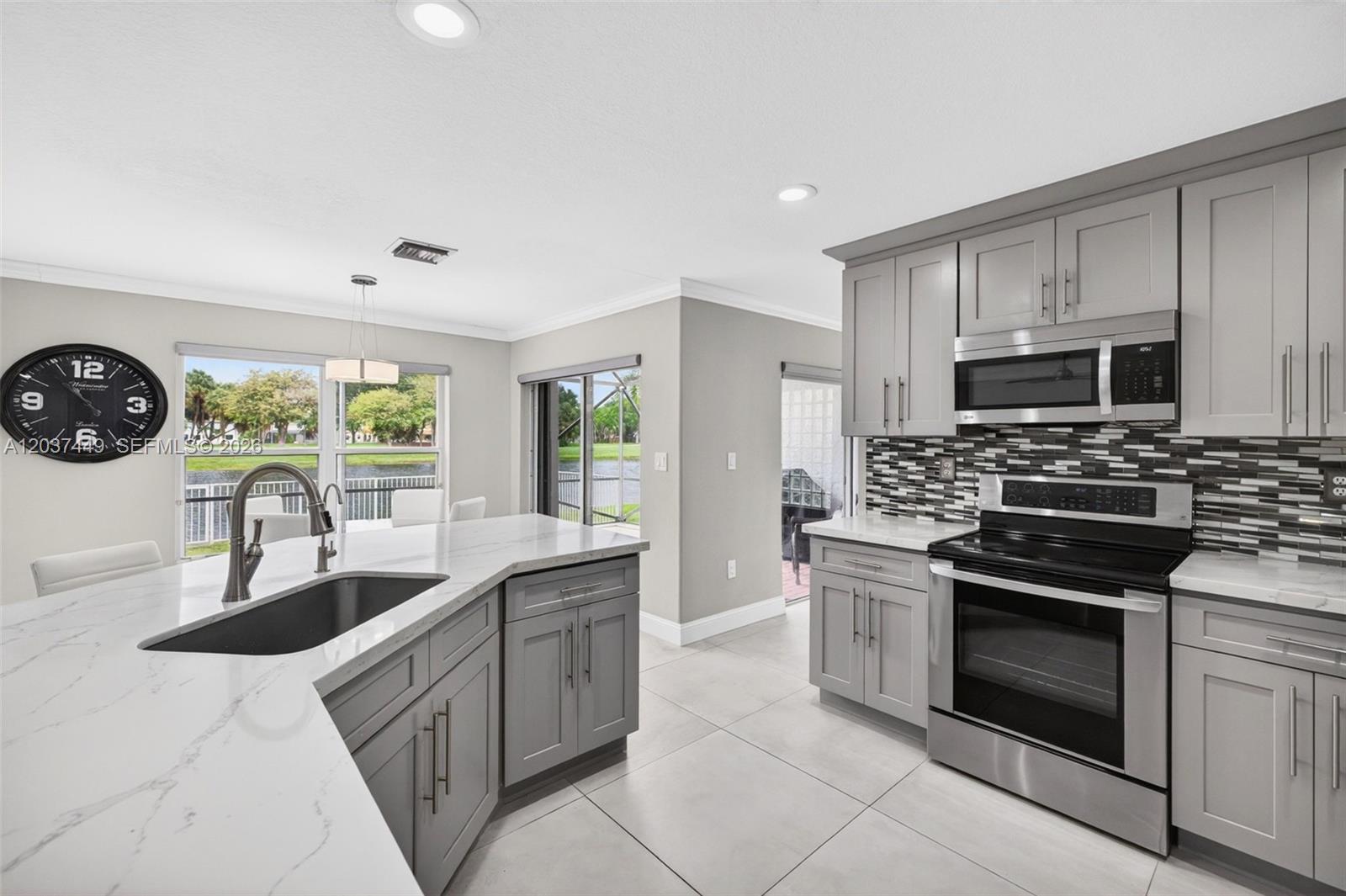 17488 Southwest 28th Court Miramar, FL 33029 - Photo 17 of 50 a kitchen with kitchen island granite countertop a sink and a stove top oven