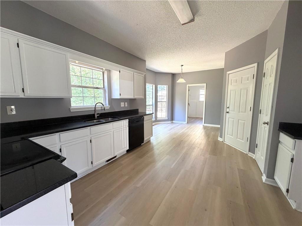 2205 Springer Walk Lawrenceville, GA 30043 - Photo 6 of 26 a kitchen with granite countertop a stove a sink a refrigerator and white cabinets with wooden floor