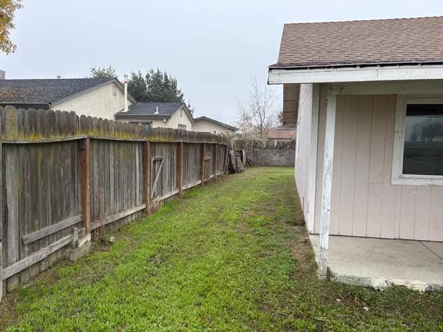 a view of a small house with wooden fence