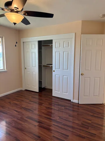 an empty room with wooden floor closet chandelier fan and windows