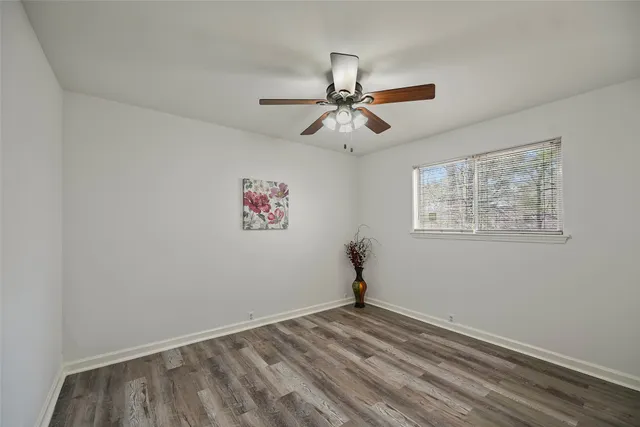 a view of an empty room and window with a chandelier fan
