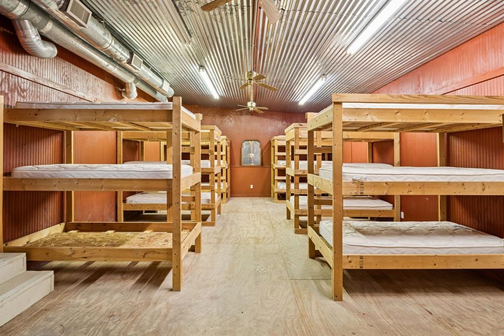 1922 A Bethel-Cannon Road Whitewright, TX 75491 - Photo 32 of 40 Accommodations room featuring multiple wooden bunk bed frames, corrugated metal ceiling, exposed ductwork, and fluorescent lighting