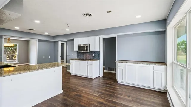 a large kitchen with a center island wooden floor stainless steel appliances and windows