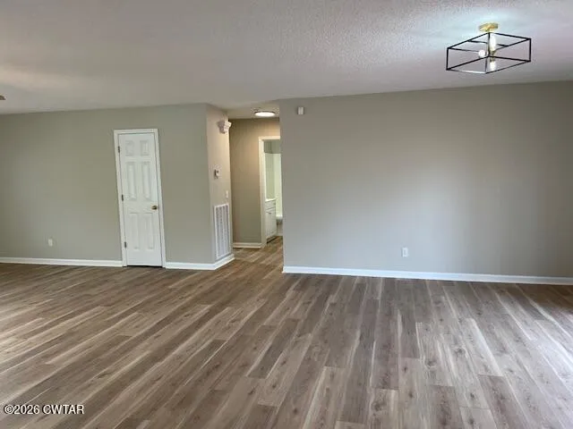 an empty room with wooden floor cabinet and windows