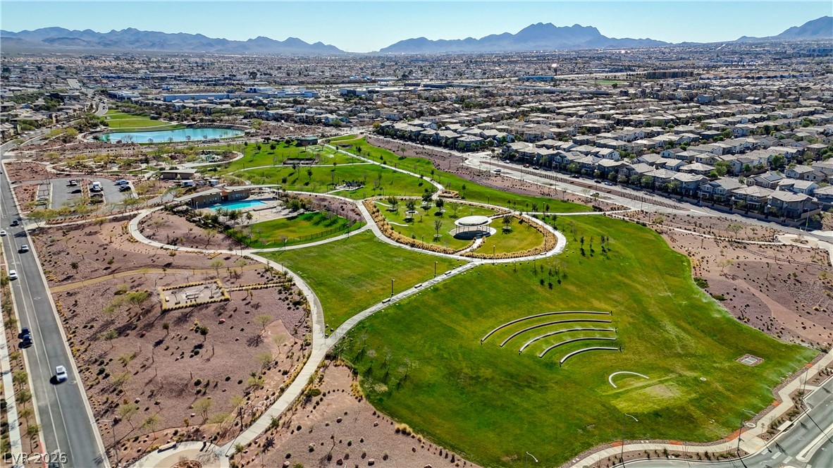 920 East Sunset Road Henderson, NV 89011 - Photo 26 of 33 Aerial view #1 vibrant community park with lush green spaces, inviting pathways, and a sparkling pool, all set against a desert mountain backdrop.