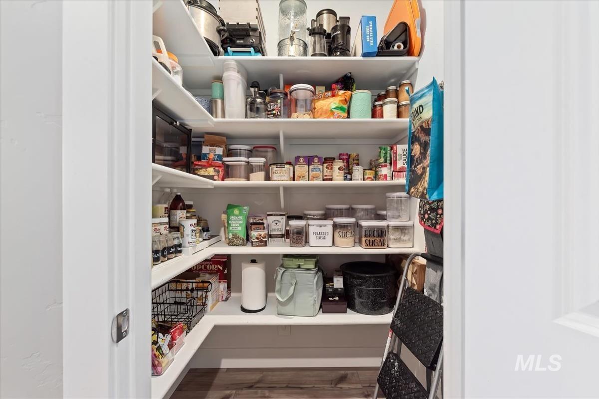 815 Knowledge Street Middleton, ID 83644 - Photo 17 of 49 Walk-in pantry featuring extensive white shelving, L-shaped configuration, and wood-finish flooring