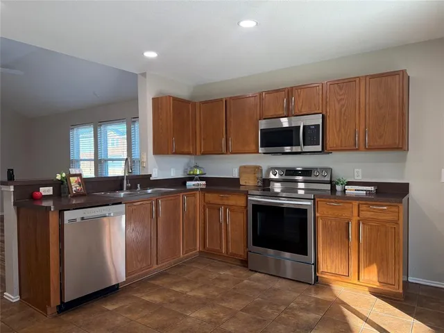 a kitchen with stainless steel appliances granite countertop a stove top oven a sink dishwasher and a microwave oven with cabinets