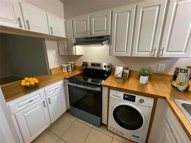 a kitchen with stainless steel appliances granite countertop a sink a stove and washer